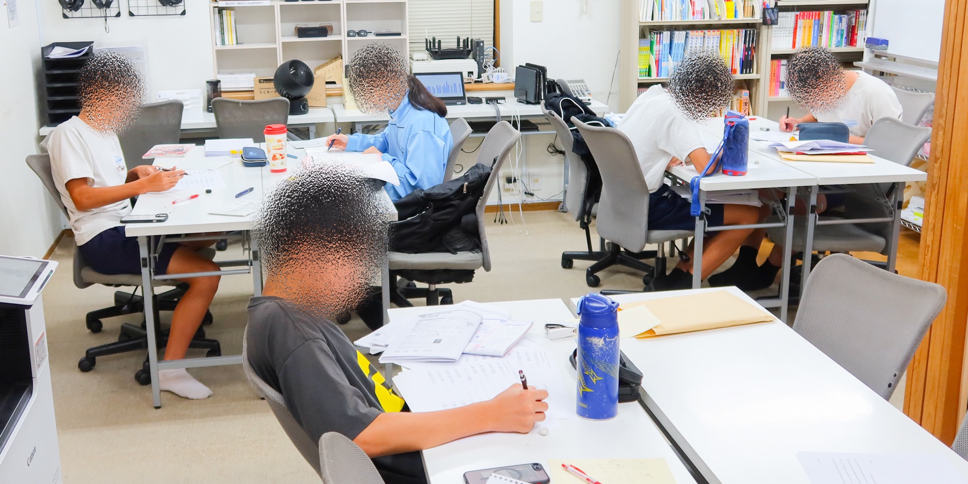 夜の教室で、机に向かって勉強している中学3年生5人。それぞれテキストやノートを開き、自分の課題に取り組んでいる様子。